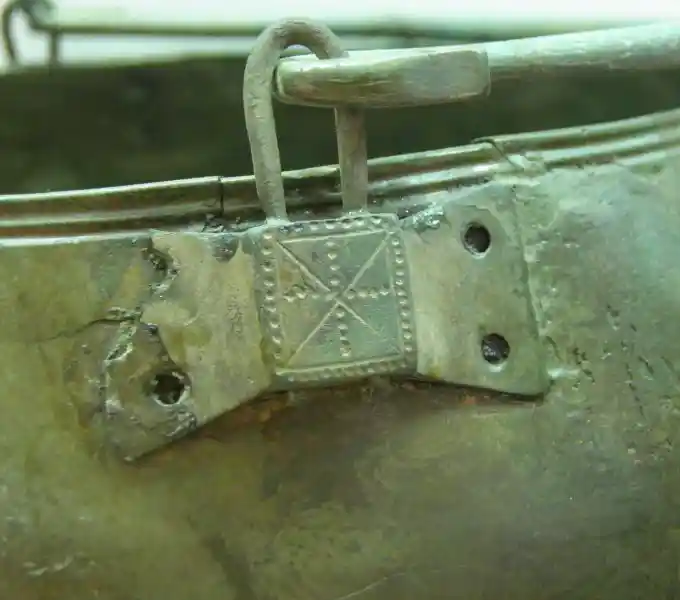 A cross made up of dots on a metal situla
